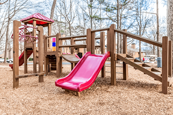 A playground with a red slide and wooden structure at Paces Pointe Apartment Homes, Matthews